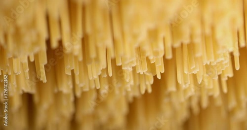 Suggestive macro closeup shot of raw italian pasta spaghetti noodles dried in a pasta factory. Soft focus on raw food.