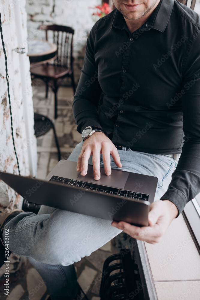 Fototapeta premium a young man in a black shirt is sitting at a table in a restaurant with a laptop