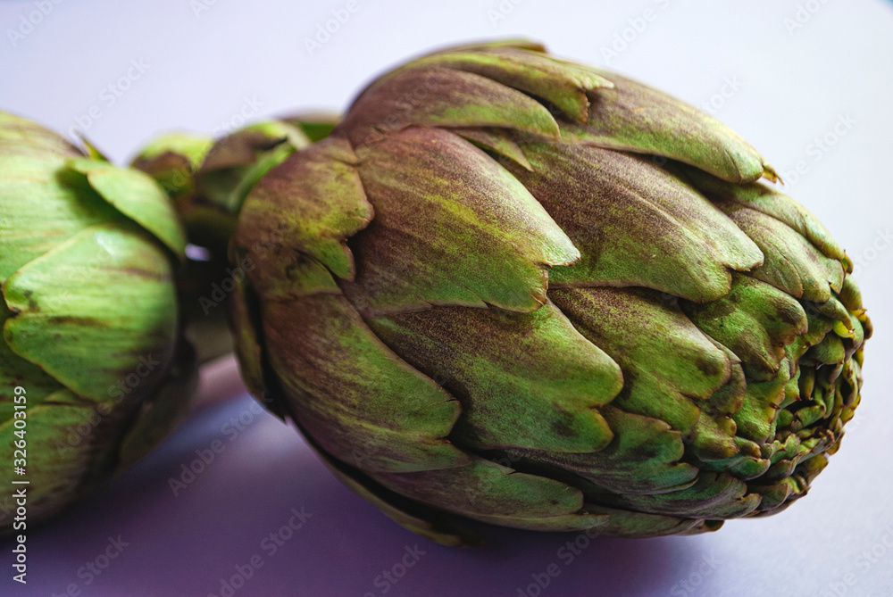 Obraz premium Artichokes close up on a purple surface.
