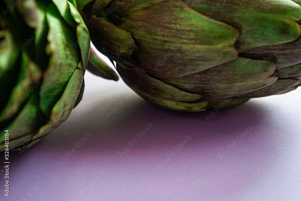 Fototapeta premium Artichokes close up on a purple surface.