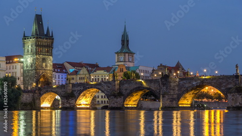 The Charles Bridge day to night timelapse over the Vltava River reflected in water in Prague, Czech Republic