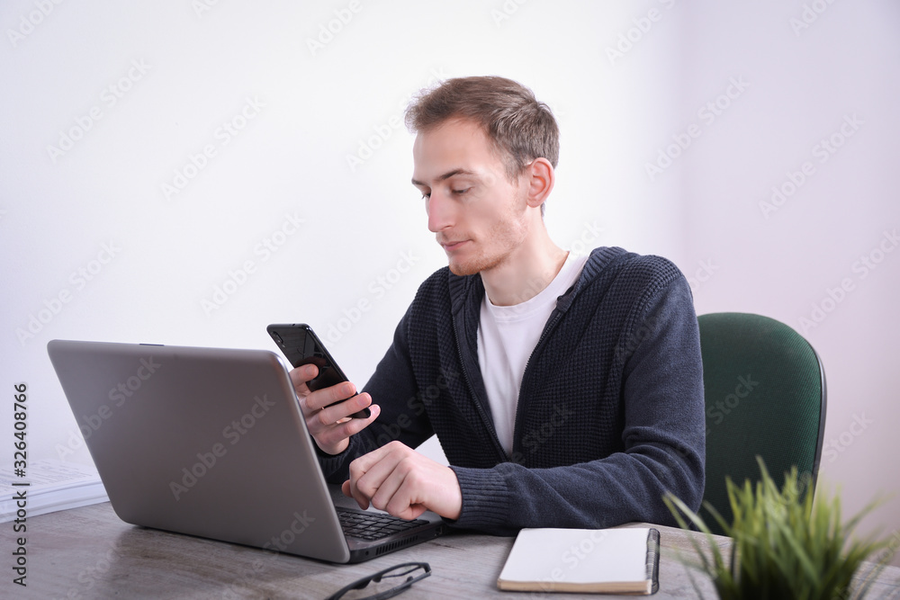 Portrait of young business man sitting at his desk desktop laptop technology in the office.Internet marketing, finance, business concept Portrait of young business man sitting at his desk desktop laptop technology in the office.Internet marketing, finance, business concept