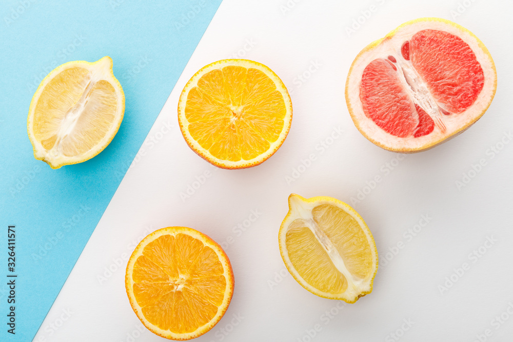 Fototapeta premium Top view of citrus halves on white and blue background
