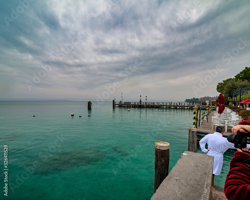 very nice view of garda lake with inside one woman make a photo and one guy ready for swimming in the lake in winter time