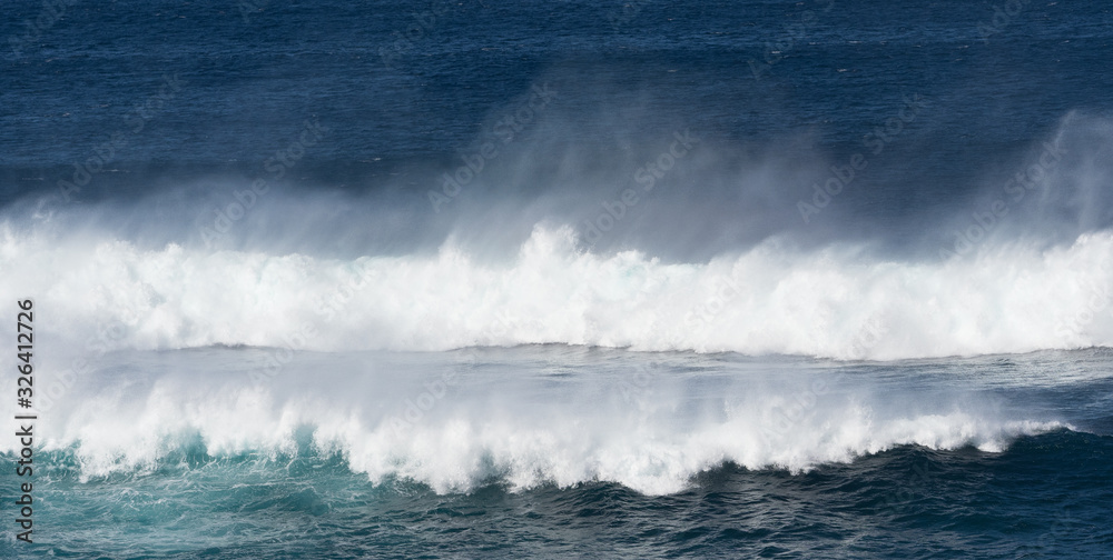 Obraz premium Dramatic white surf and spray as blue ocean waves roll