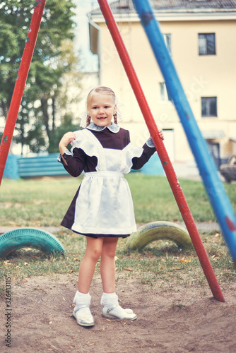 portrait of a little schoolgirl girl in uniform at the playground.