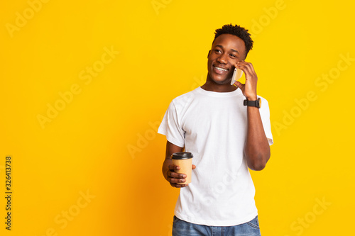 Portrait of handsome african guy standing with coffee to go