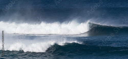 Dramatic white surf and spray as blue ocean waves roll.Image