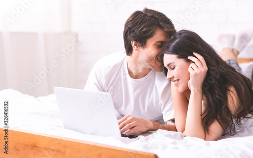 Young couple networking on laptop together, empty space