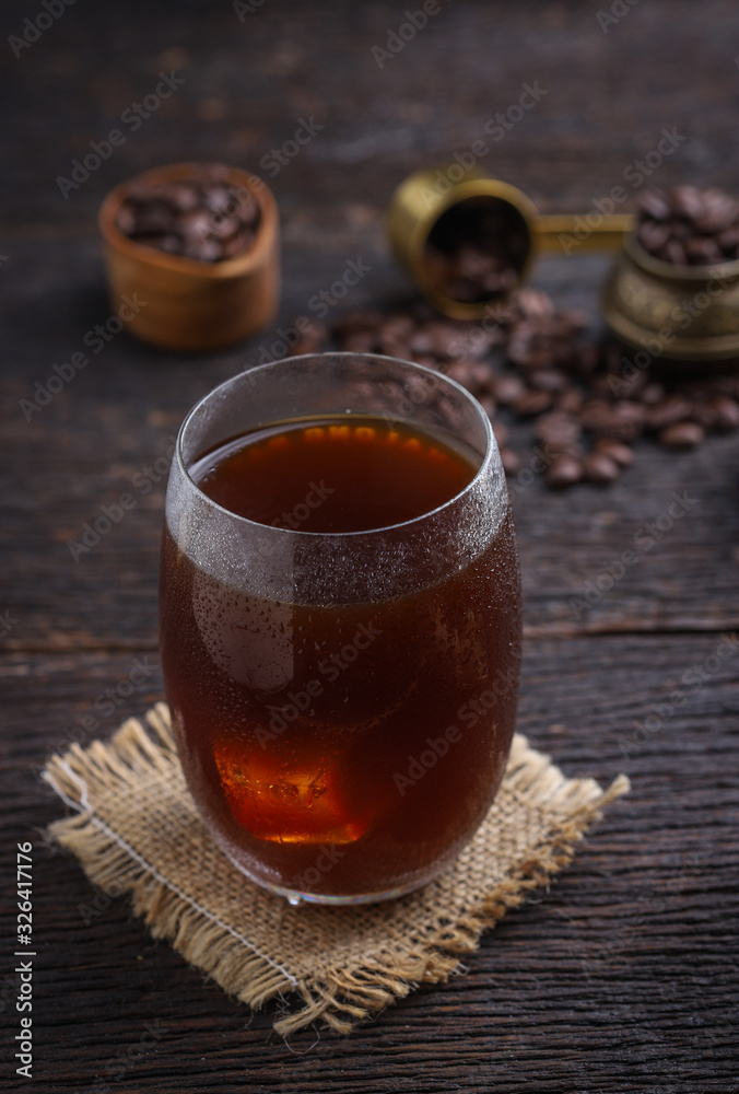 cold brew coffee into glass on wooden table.
