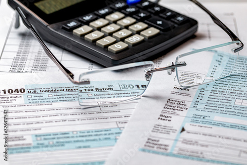 1040 income tax form 2019 with calculator and focus through glasses. Concept of filing taxes, payment, refund, and April 15, 2020 tax deadline photo