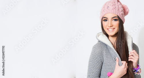 portrait of young woman with knotted woolen hat and scarf, winter fashion style, isolated on white