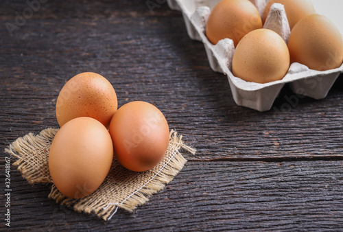 Raw eggs in egg box on rustic wooden background.