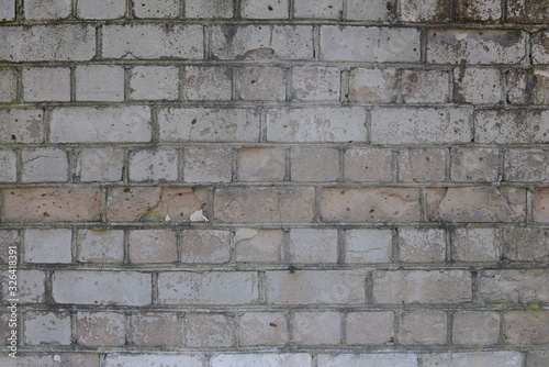 Old shabby, wrecked brick wall with grey cement mortar as background