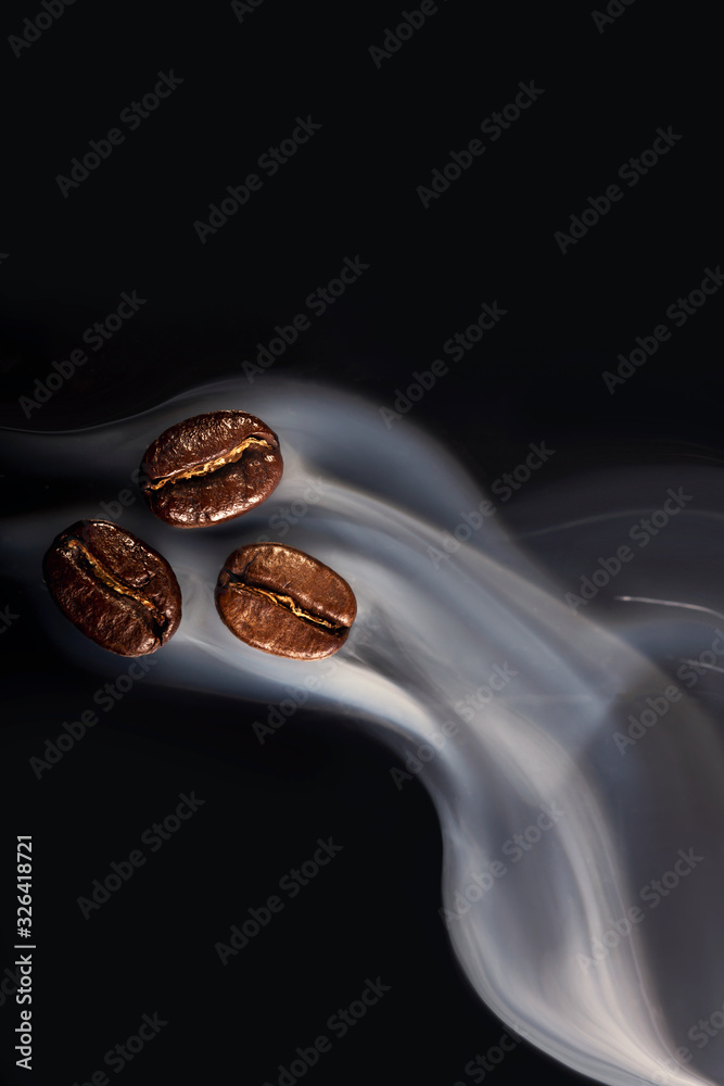 Roasted coffee beans. Seeds of freshly roasted coffee with smoke. Coffee beans closeup with emphasis on the grain with smoke. Roasted coffee beans. Seeds of freshly roasted coffee with smoke. Coffee beans closeup with emphasis on the grain with smoke.