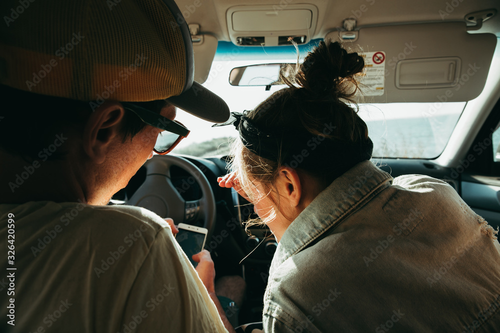 The couple decides where to go. They look at the phone. Navigation. In the car The couple decides where to go. They look at the phone. Navigation. In the car