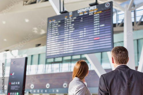 Business people looking on flight display screen in airport