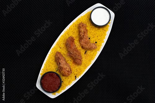 Yellow rice and fried chicken strips in a bowl with black background