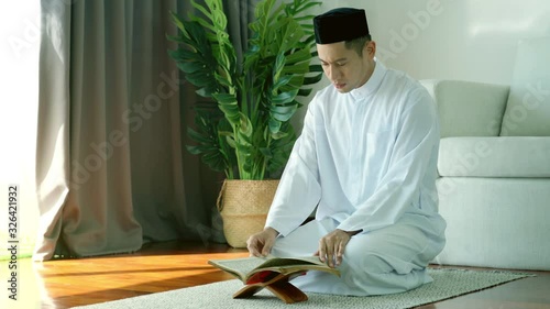 Portrait of Asian Muslim man reciting surah al-Fatiha passage of the Qur'an, in a daily prayer at home in a single act of sujud called a sajdah or prostration photo