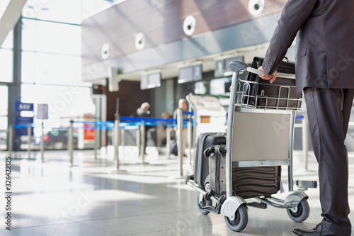 Mature businessman pushing baggage cart for check in at airport