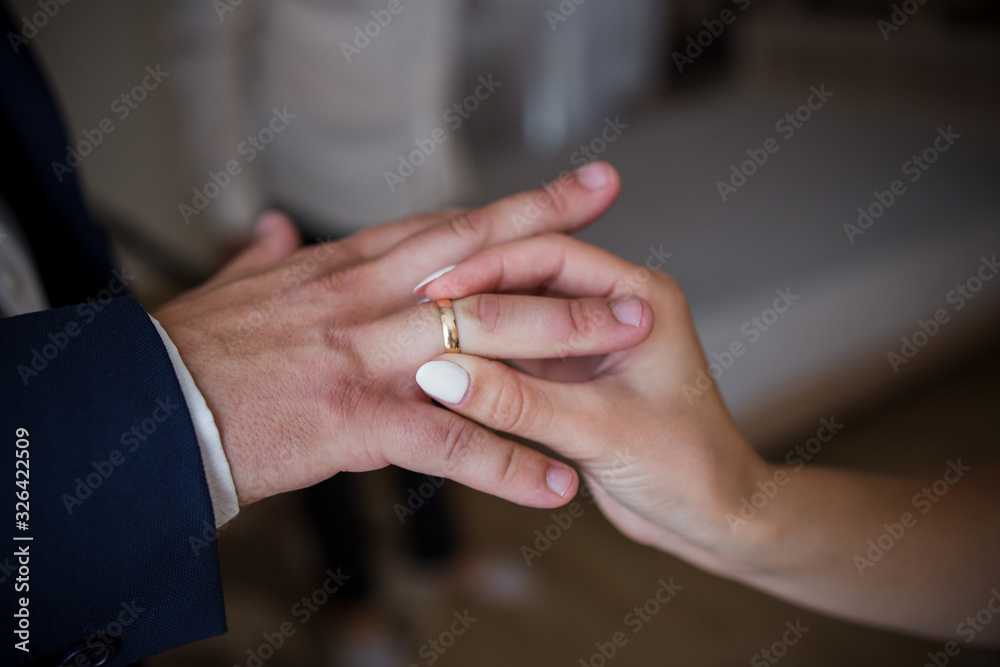 Fototapeta premium the groom puts a ring on the bride’s hand