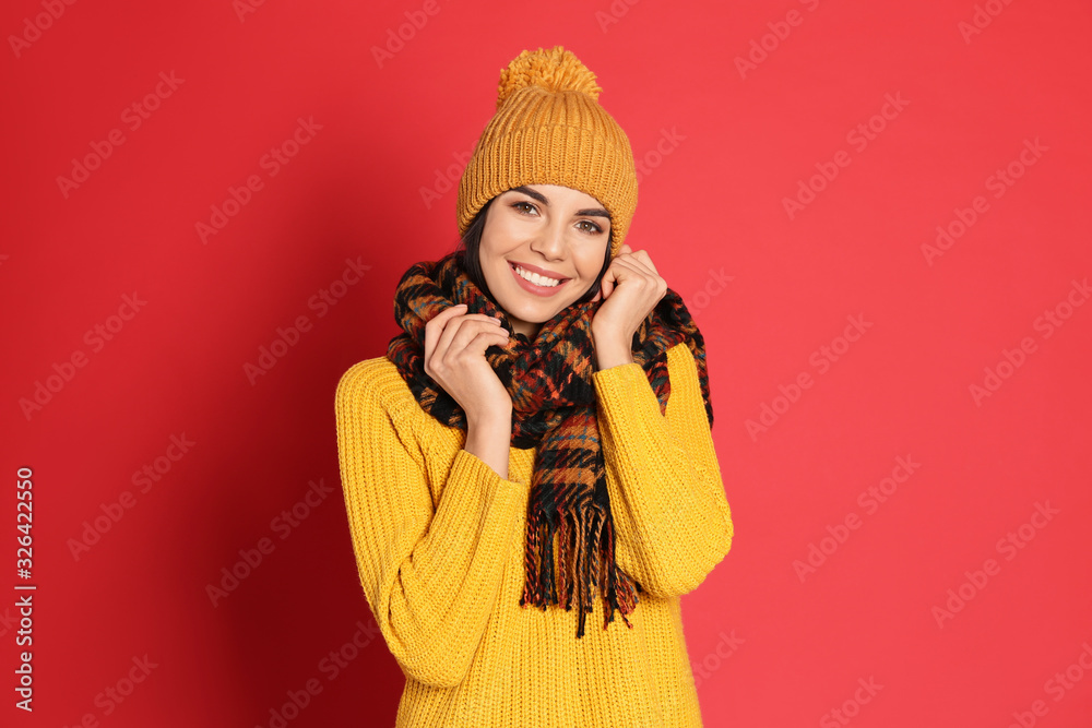 Young woman wearing warm sweater, scarf and hat on red background. Winter season Young woman wearing warm sweater, scarf and hat on red background. Winter season