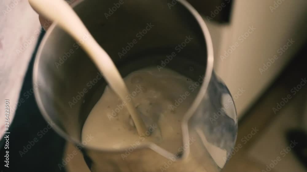 Barista holding a jug of foam texturing milk with the machine vaporizer, view from the top Barista holding a jug of foam texturing milk with the machine vaporizer, view from the top