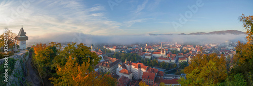 Cityscape of Graz and the famous clock tower (Grazer Uhrturm) on Shlossberg hill, Graz, Styria region, Austria, in autumn. Panoramic view.