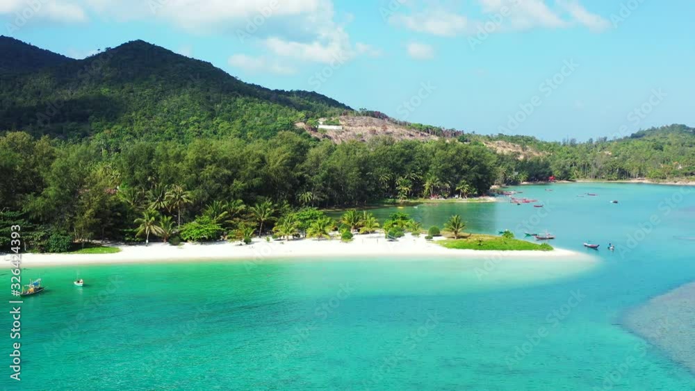 Boats floating on calm bay of tropical island with palm trees on shoreline, white sandy beach washed by turquoise lagoon, Thailand Boats floating on calm bay of tropical island with palm trees on shoreline, white sandy beach washed by turquoise lagoon, Thailand