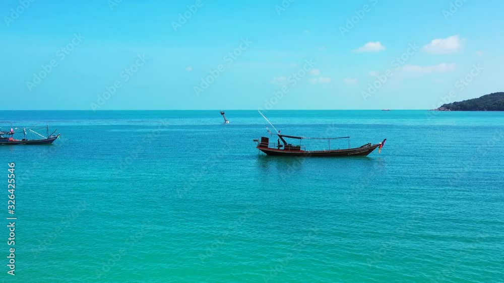 Fishing boats floating on calm blue turquoise lagoon with bright sky and clouds background on a peaceful sea scenery from Thai coastline Fishing boats floating on calm blue turquoise lagoon with bright sky and clouds background on a peaceful sea scenery from Thai coastline