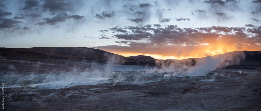 Geyser and volcanic lands at sunrise.
