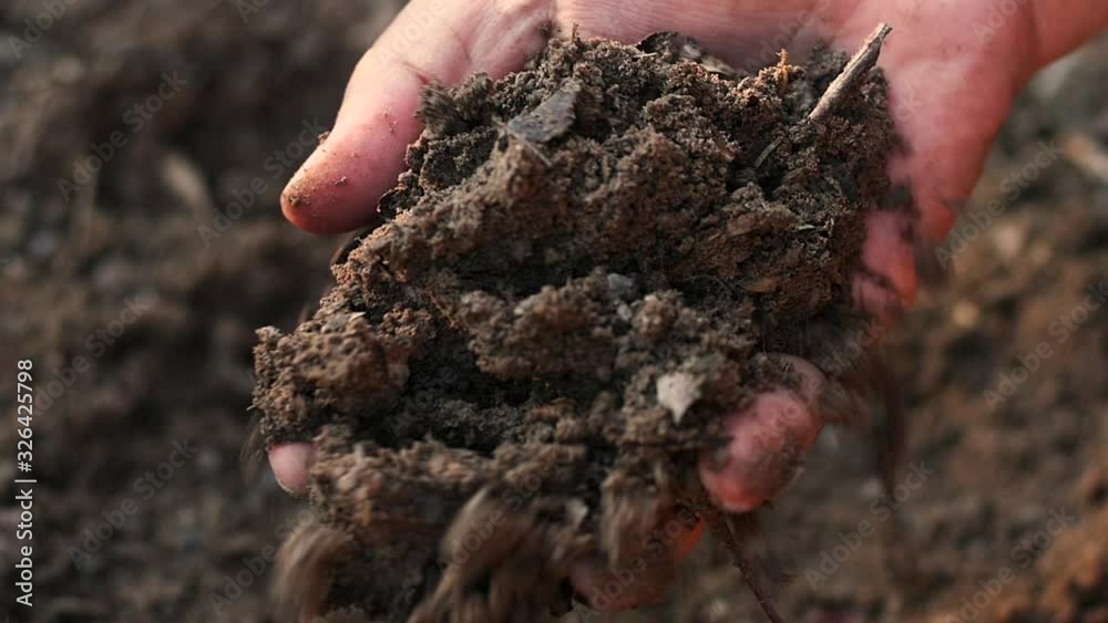 Farmer hand testing organic soil by pouring to below slow motion shot