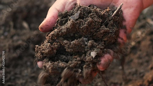 Farmer hand testing organic soil by pouring to below slow motion shot