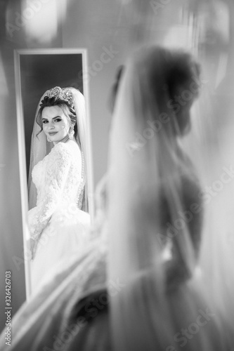 eautiful bride near mirrror. Fashion photo of beautiful bride posing in room photo