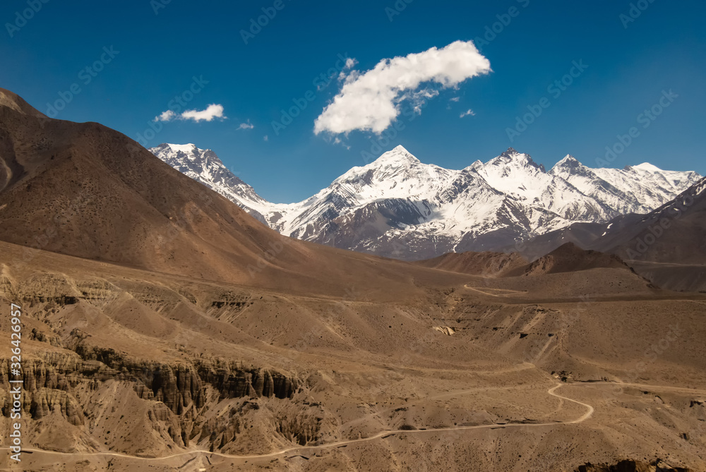 A view of the snow covered peaks of the Nilgiri range from the Himalayan village of Tiri in Upper Mustang in Nepal on a sunny day.