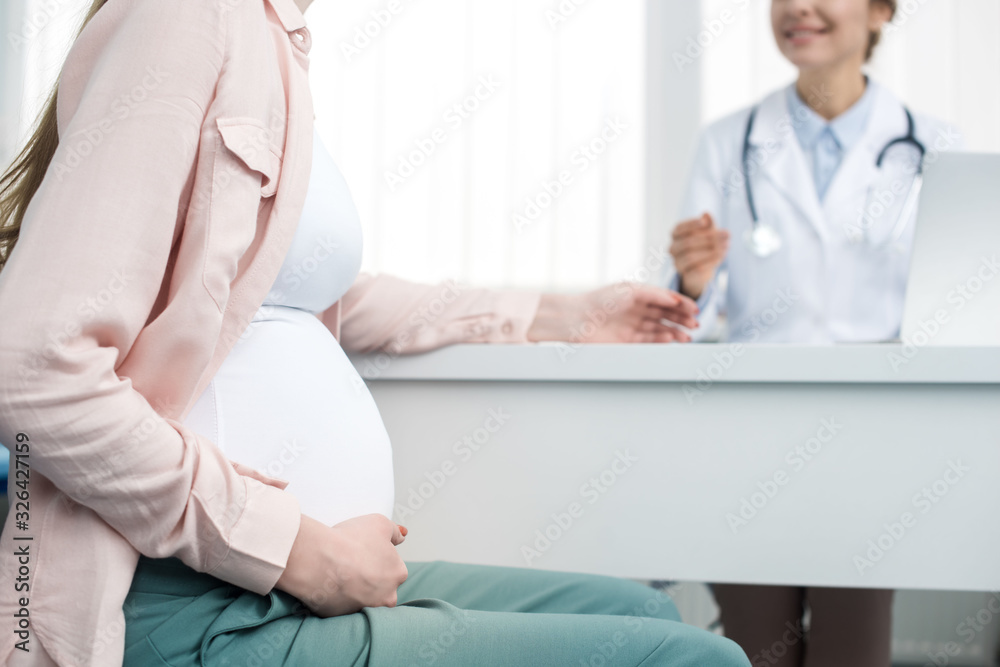 Fototapeta premium cropped view of young pregnant woman having consultation with gynecologist in clinic