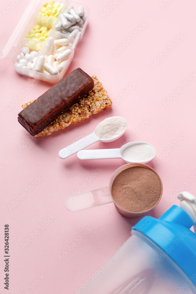 Fitness and healthy lifestyle Supplements - pills tablets, energetic bars, protein powder, shaker on pink background, selective focus, concept of nutrition fit bodycare diet, modern health food Fitness and healthy lifestyle Supplements - pills tablets, energetic bars, protein powder, shaker on pink background, selective focus, concept of nutrition fit bodycare diet, modern health food