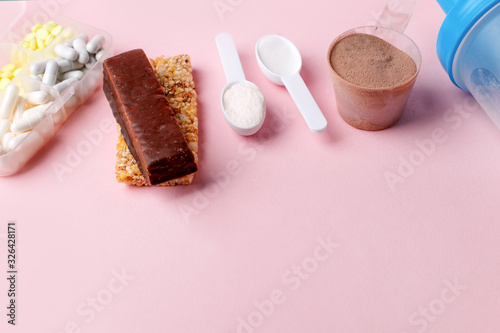 Fitness and healthy lifestyle Supplements - pills tablets, energetic bars, protein powder, cosein, shaker on pink background, copy space, concept of nutrition fit bodycare diet, modern health food