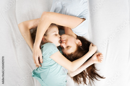 Family time: Mom and daughter are lying on the bed hugging and kissing.