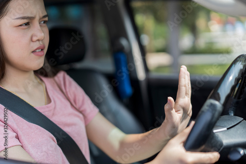 Angry and hopeless young asian female Driver Pressing Horn And Screaming at someone While Driving. concept of Car traffic at rush hour in downtown area of the city and people. Car pollution