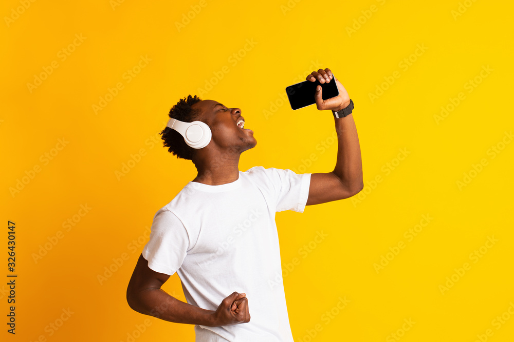 Young emotional african guy in headphones singing his favorite song Young emotional african guy in headphones singing his favorite song