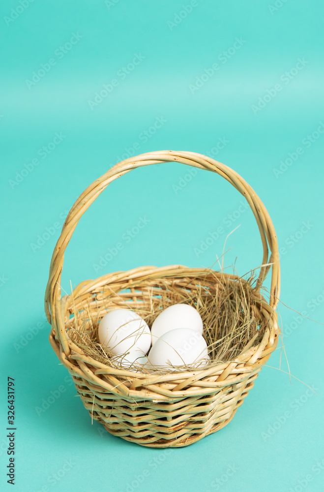 Easter holiday: a small basket with white eggs on a blue background. Easter holiday: a small basket with white eggs on a blue background.