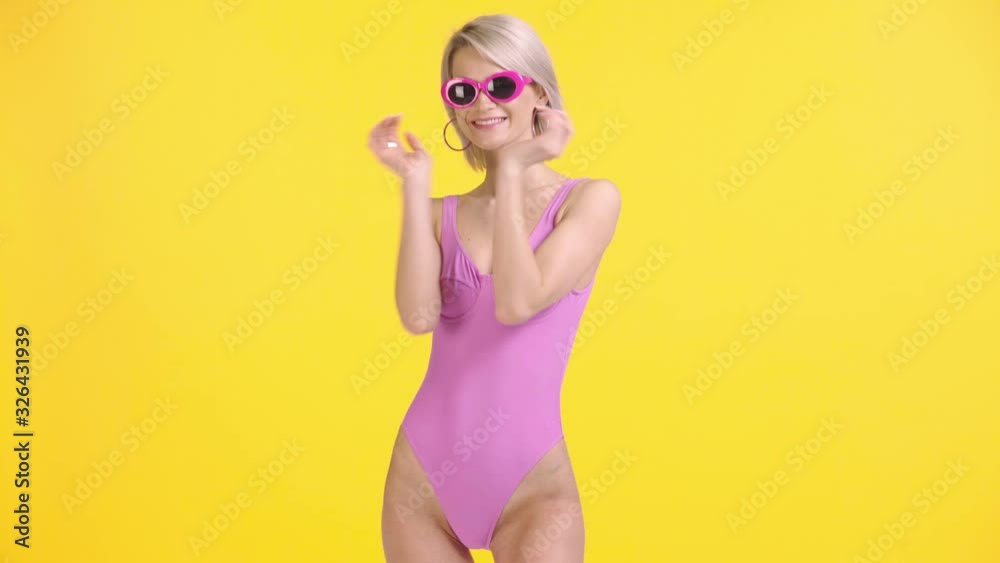 happy girl in swimsuit and sunglasses blowing air kiss isolated on yellow happy girl in swimsuit and sunglasses blowing air kiss isolated on yellow