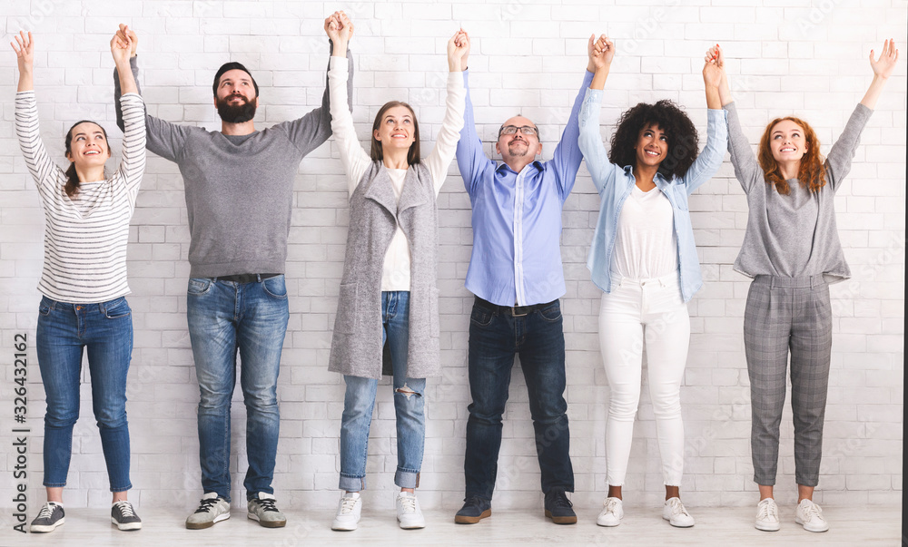 Obraz premium Teambuilding. Group portrait of happy people holding and raising hands together