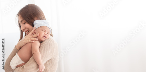 Close up beautiful young asian mother holding her newborn one month baby sleep on her shoulder. Healthcare and medical love asia woman lifestyle mother's day concept.