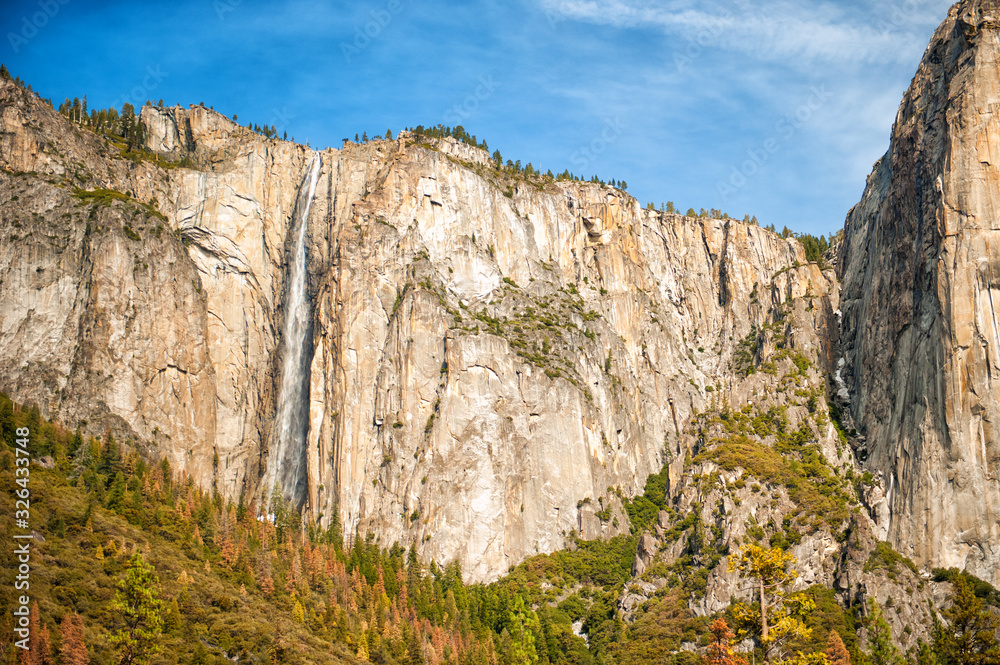 Scenic landscape with waterfall and rocks in Yosemite valley, Yosemite national park, California, USA. Travel tourism hiking destination. View of waterfall in sunny day