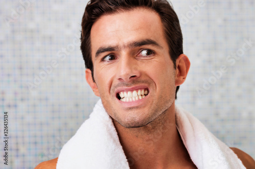 Portrait of handsome man looking on the mirror while checking on his teeth