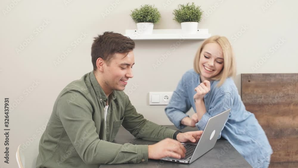 Funny newlyweds spend fun in the kitchen at the laptop, buying tickets for holidays. Funny newlyweds spend fun in the kitchen at the laptop, buying tickets for holidays.