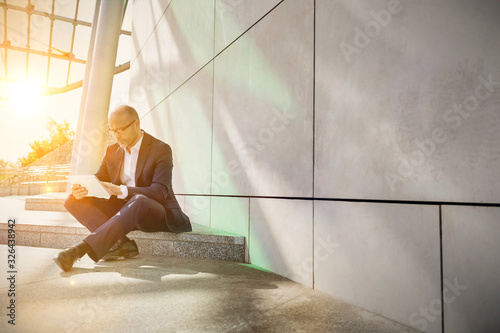 Portrait of businessman using digital tablet while sitting outside the office photo