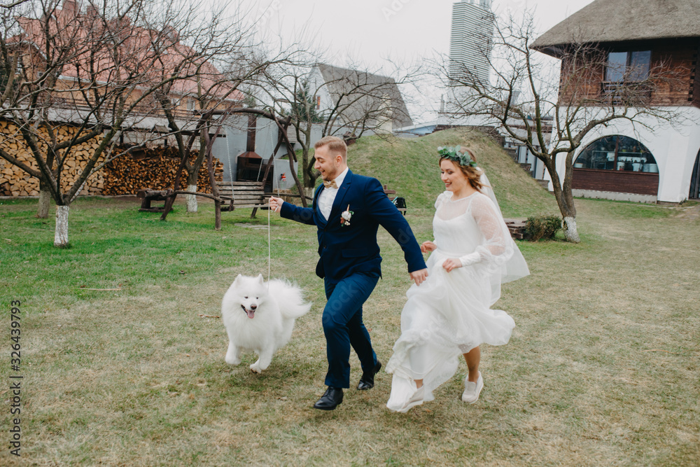 Newlyweds run on lawn next to dog on background of house. Newlyweds run on lawn next to dog on background of house.